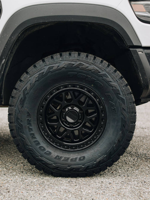 Close-up of a black wheel with a Toyo Open Country R/T tire on a white RAM 1500 TRX