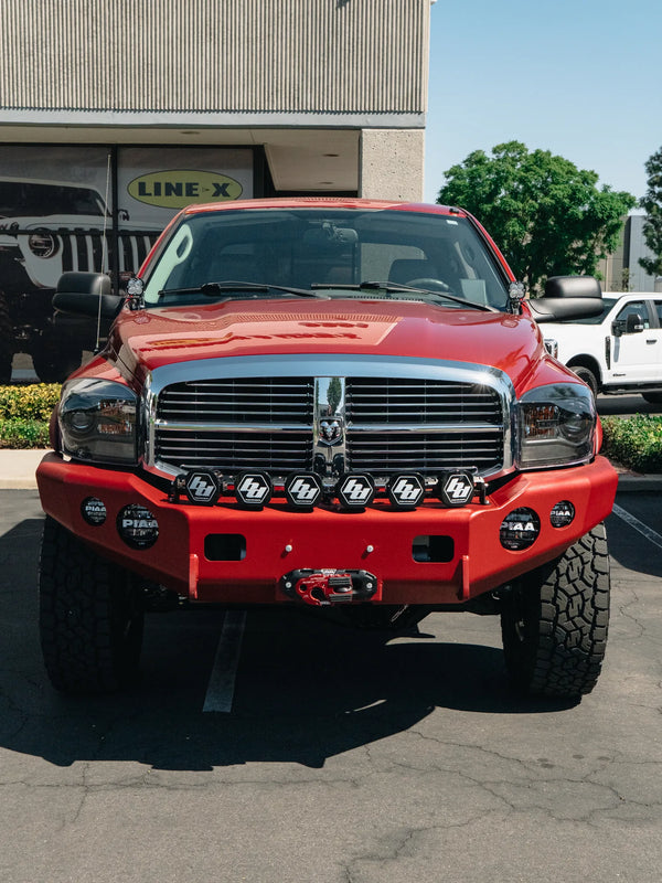 Front view of a red Dodge Ram with a heavy-duty bumper, winch, and auxiliary lights installed at Empire Motorsports
