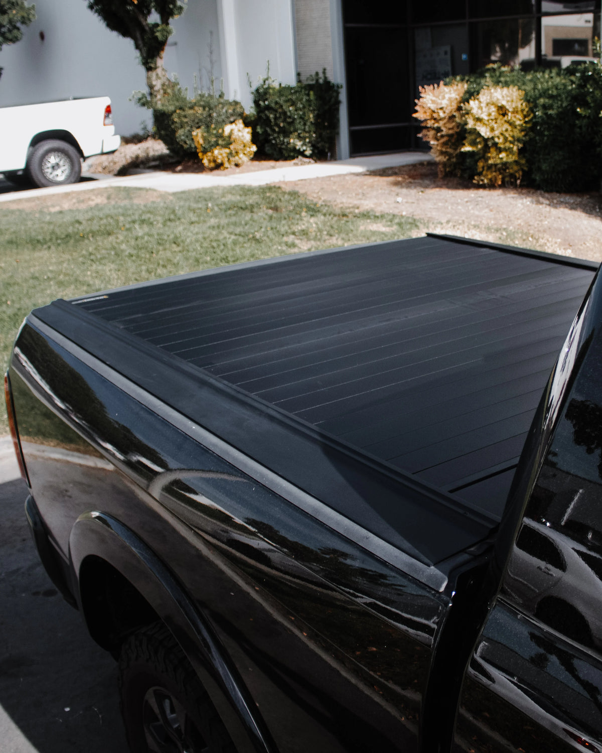 Black retractable tonneau cover installed flush over the bed of a black pickup truck.