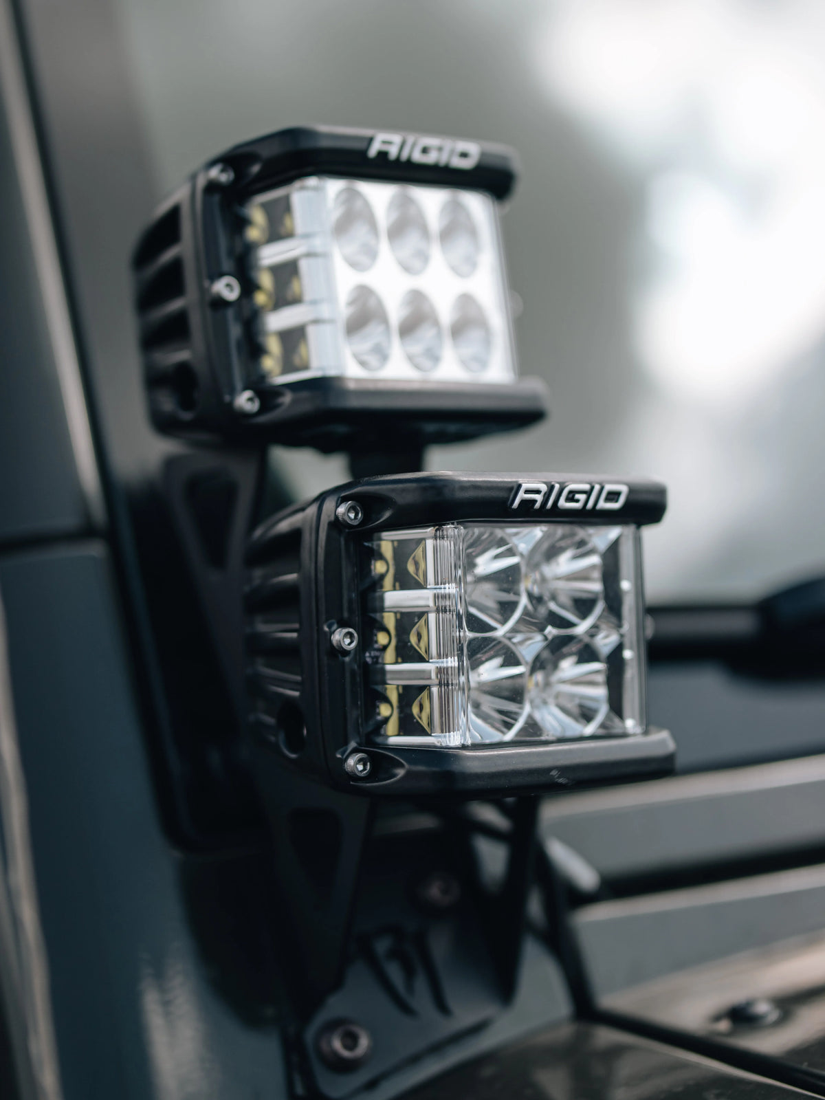 Close-up of two RIGID LED pod lights mounted on an off-road vehicle.