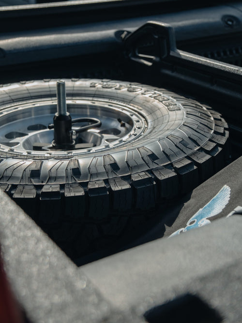 Spare tire, a Toyo Open Country M/T on a wheel, stored under a Ram HD