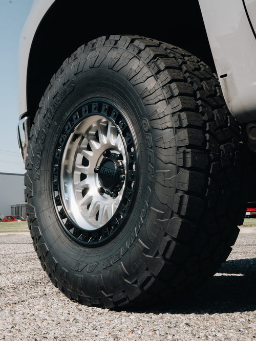 Silver KMC wheel with a Toyo Open Country all-terrain tire on a white truck